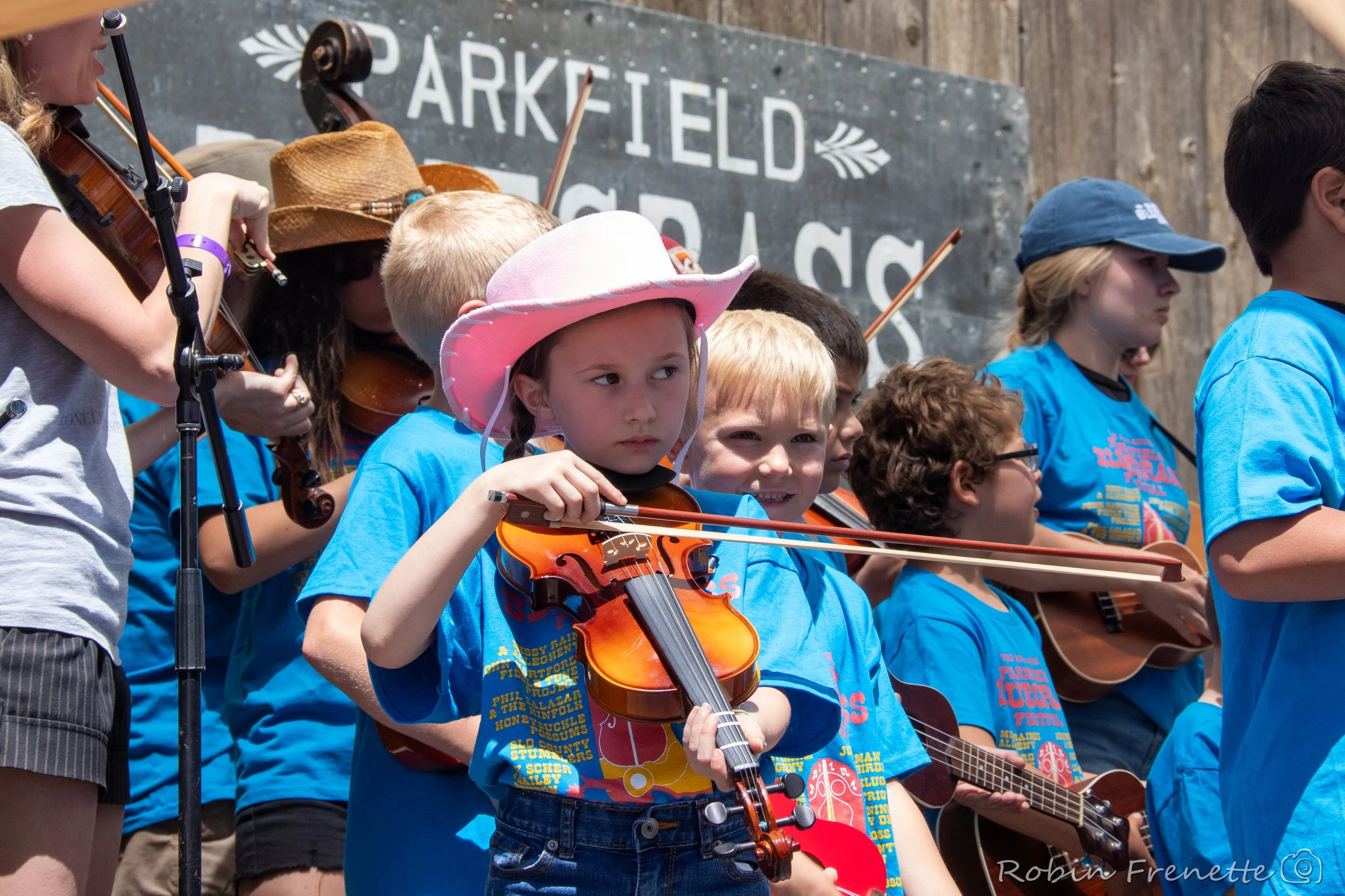 Children playing musical instruments on stage during the kids on bluegrass performance at the Parkfield Bluegrass Festival