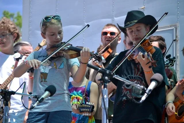 Old photo of children playing violins on stage during the Parkfield Bluegrass Festival Kids on Bluegrass Performance