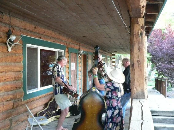 Group of four people playing guitar and singing on a the back porch of the Parkfield Lodge during the Parkfield Bluegrass Festival