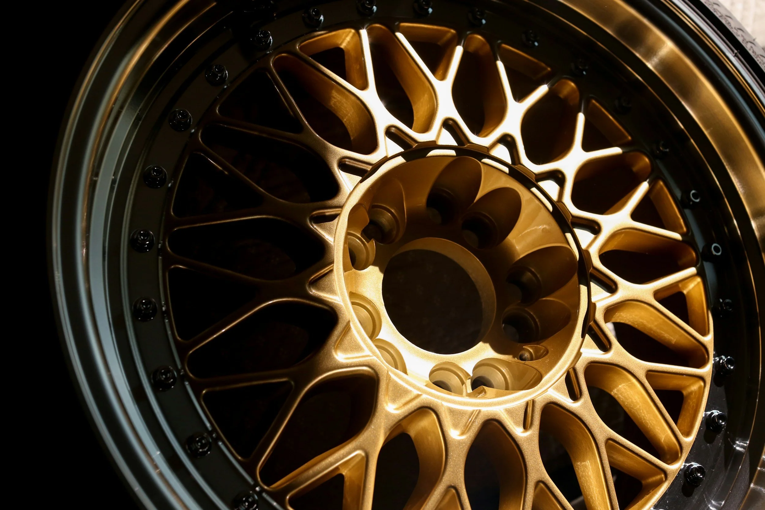 Close-up of a gold-colored alloy car wheel with a complex spoke design.