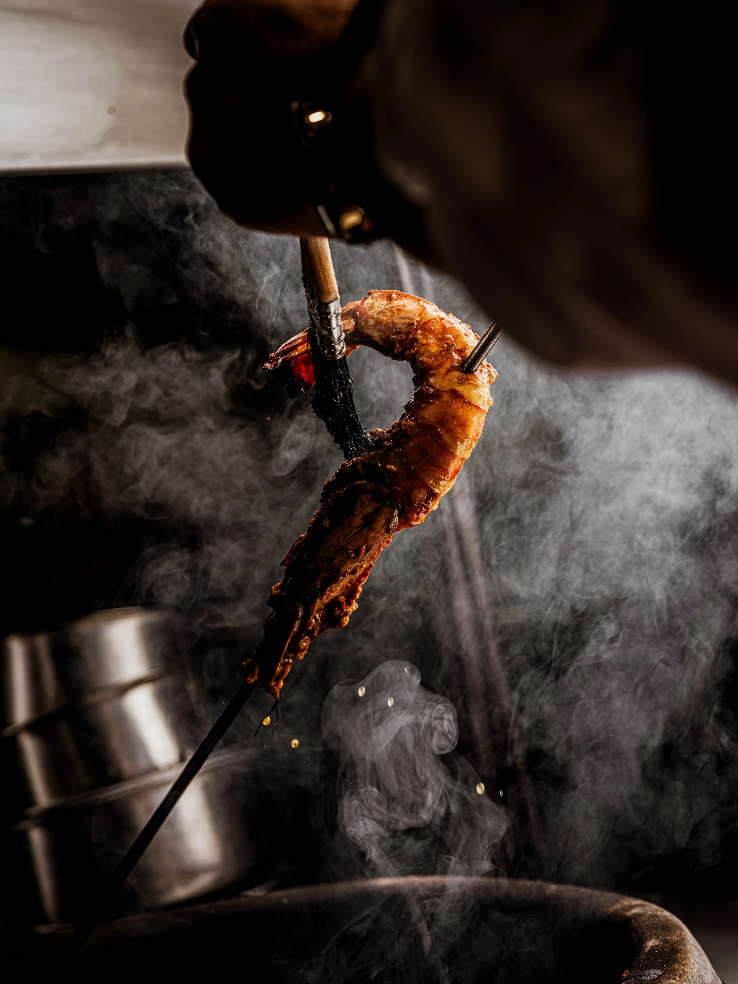 A prawn being glazed with smoke in the background