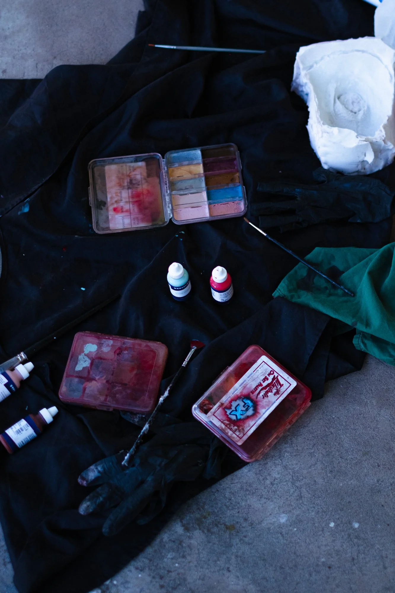 Matériel de tatouage, comprenant des encres, des aiguilles, des gants, et une compresse de coton, disposé sur un drap noir.