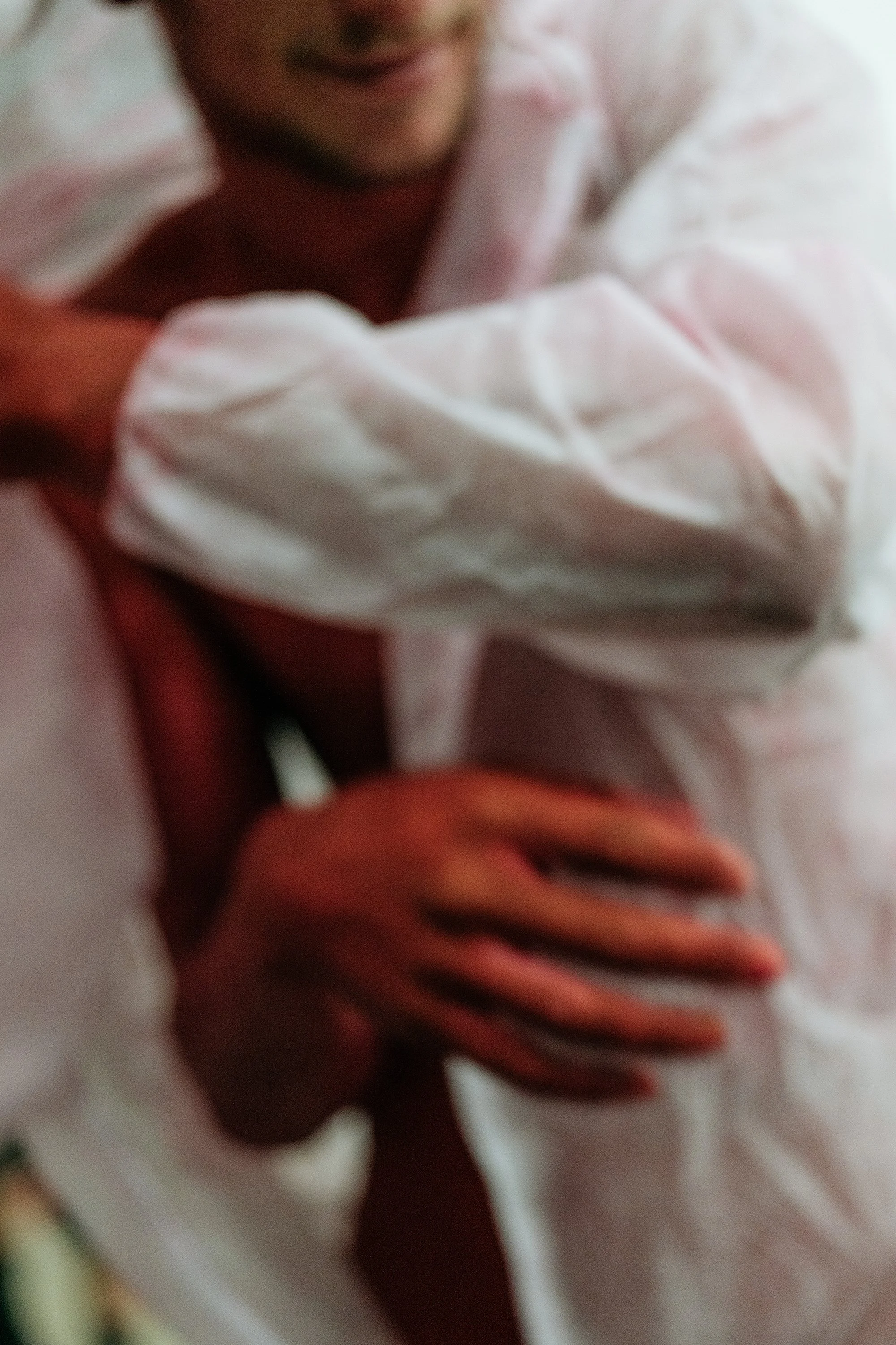 Un bébé en pyjama blanc, tenant doucement son ventre avec ses mains, souriant.