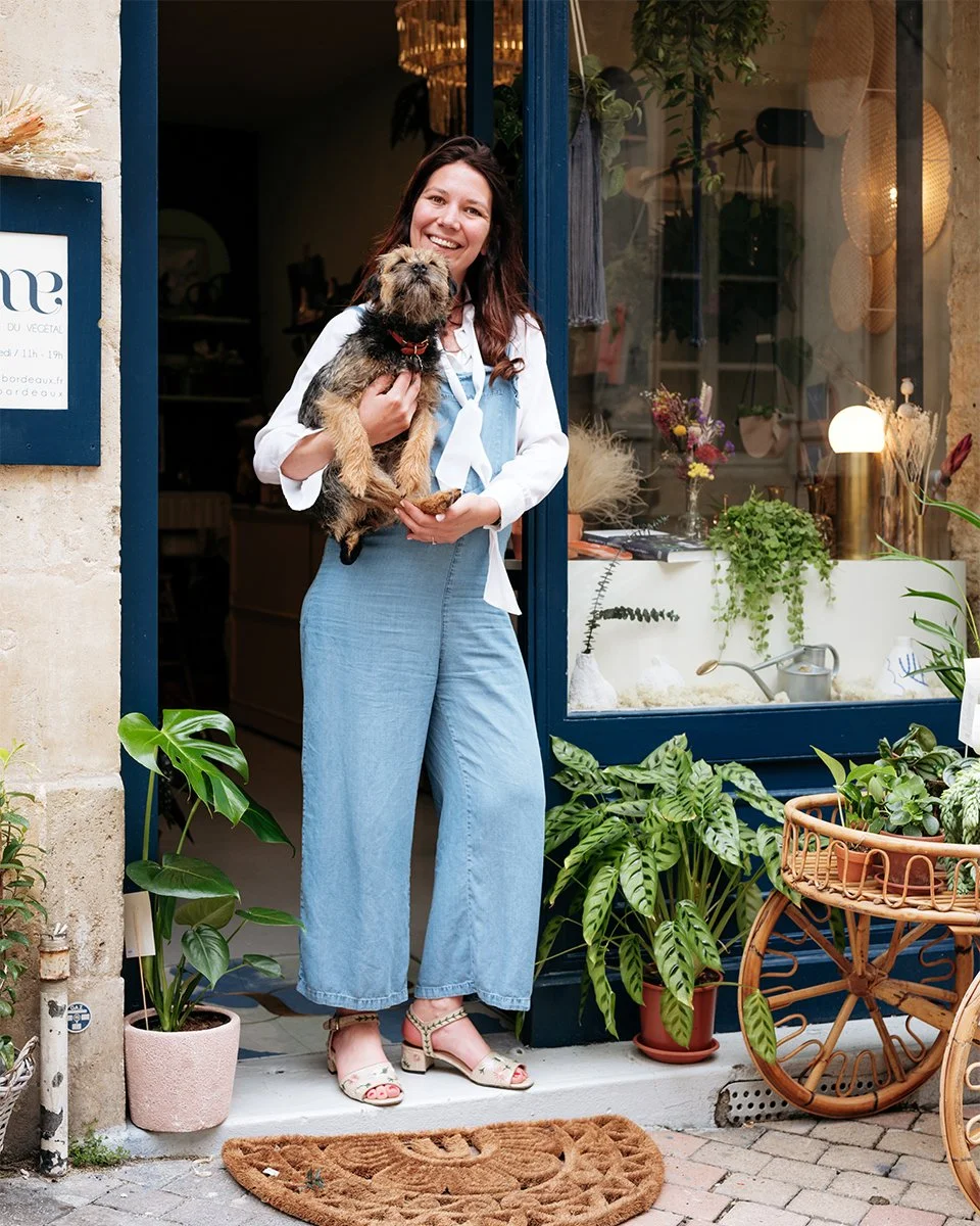 Femme heureuse tenant un chien en dehors d'une boutique de fleurs ou de décoration