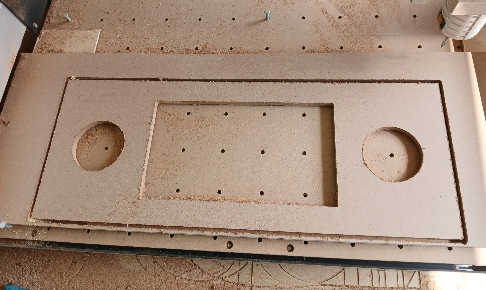 Woodworking jig with two circular cutouts and multiple small holes on a worktable.