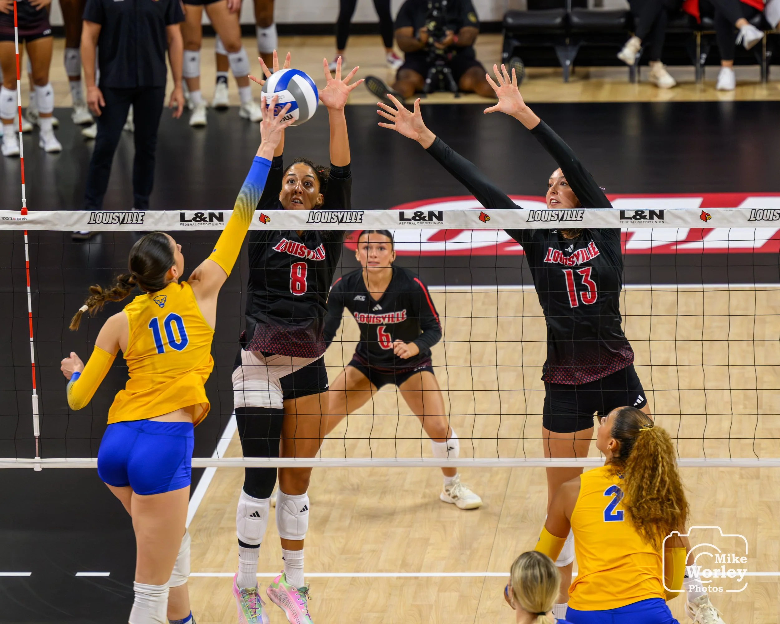 Nayelis Cabello (8) with a solo block covered by Cara Cresse (13) and backed by Hannah Kenny (6)