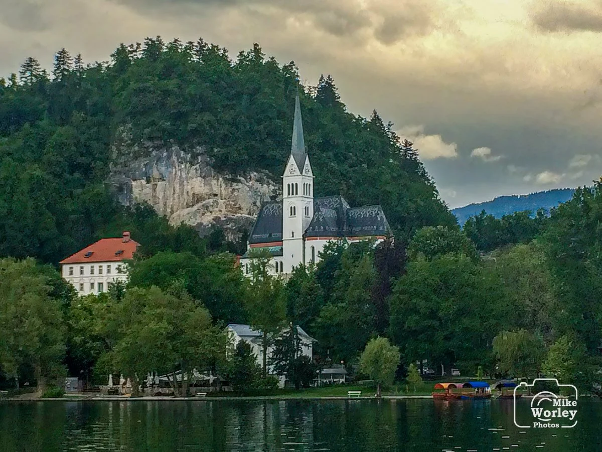 A church on the shore of Lake Bled next to the promontory of Bled Castle.