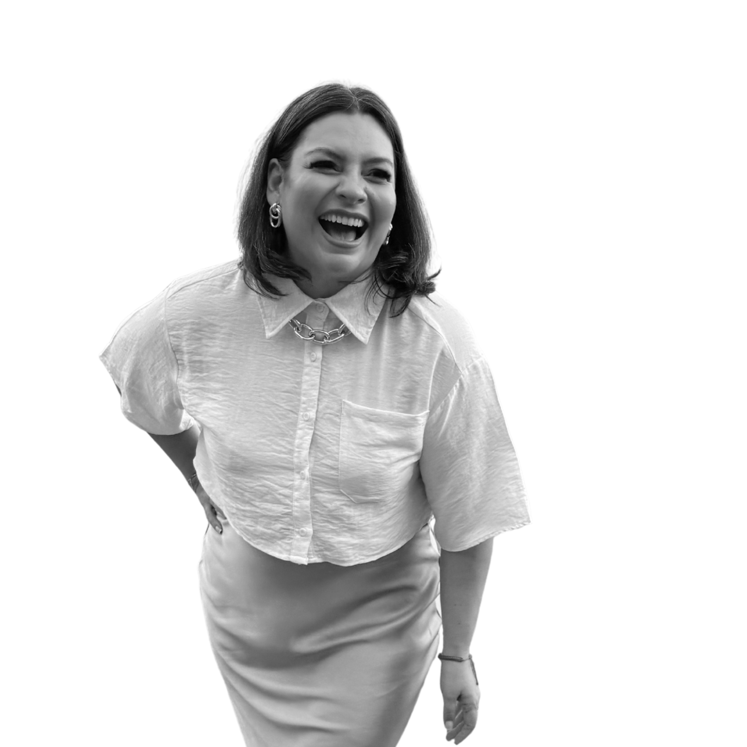 Dr. Mariela Salas. A woman laughing and smiling, wearing a white button-up shirt and a skirt, with her hand on her hip, and dark hair styled in a shoulder-length bob, against a black background.