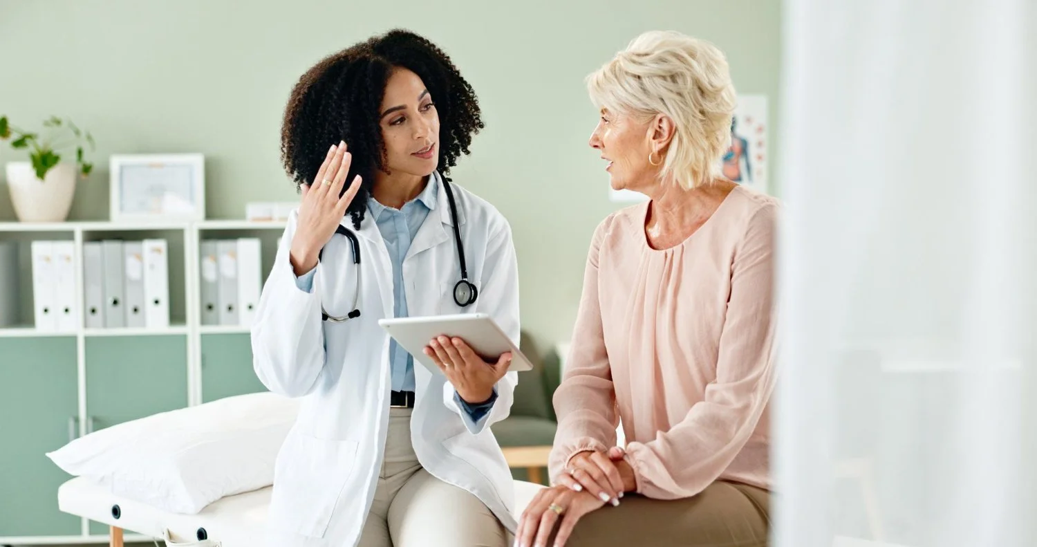 Medical professional and elderly patient having a conversation in a clinic room.