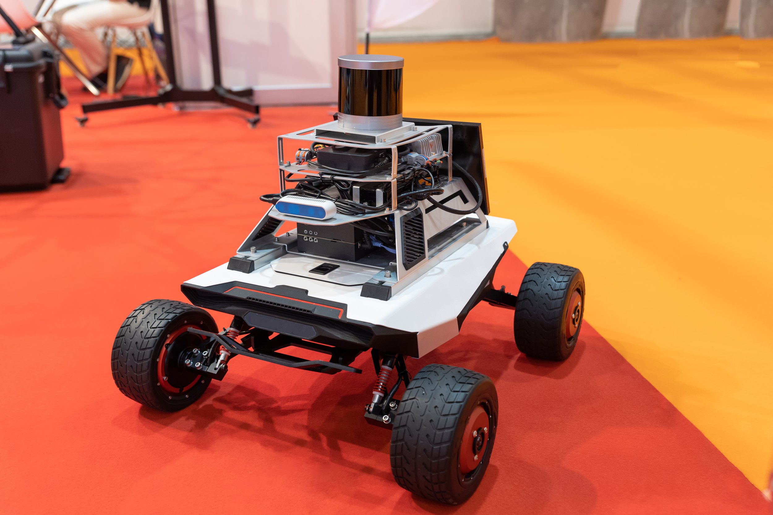 Un robot mobile à quatre roues sur un sol orange.