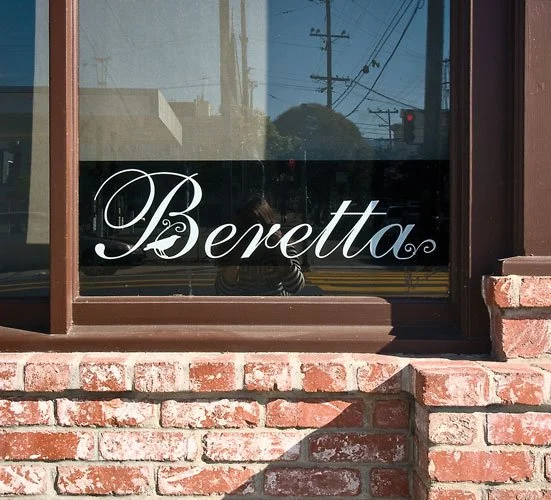 A storefront window with the word 'Benetta' written in white cursive lettering.