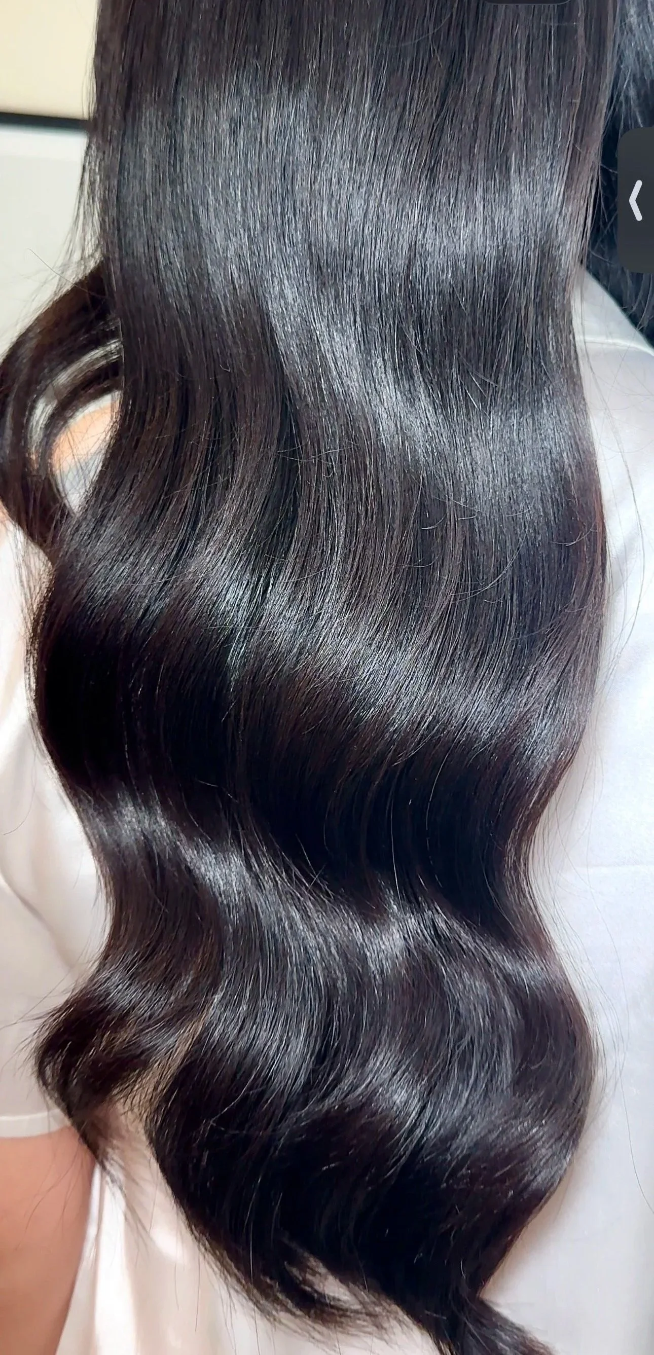 Close-up of shiny, dark brown, wavy hair with smooth texture.