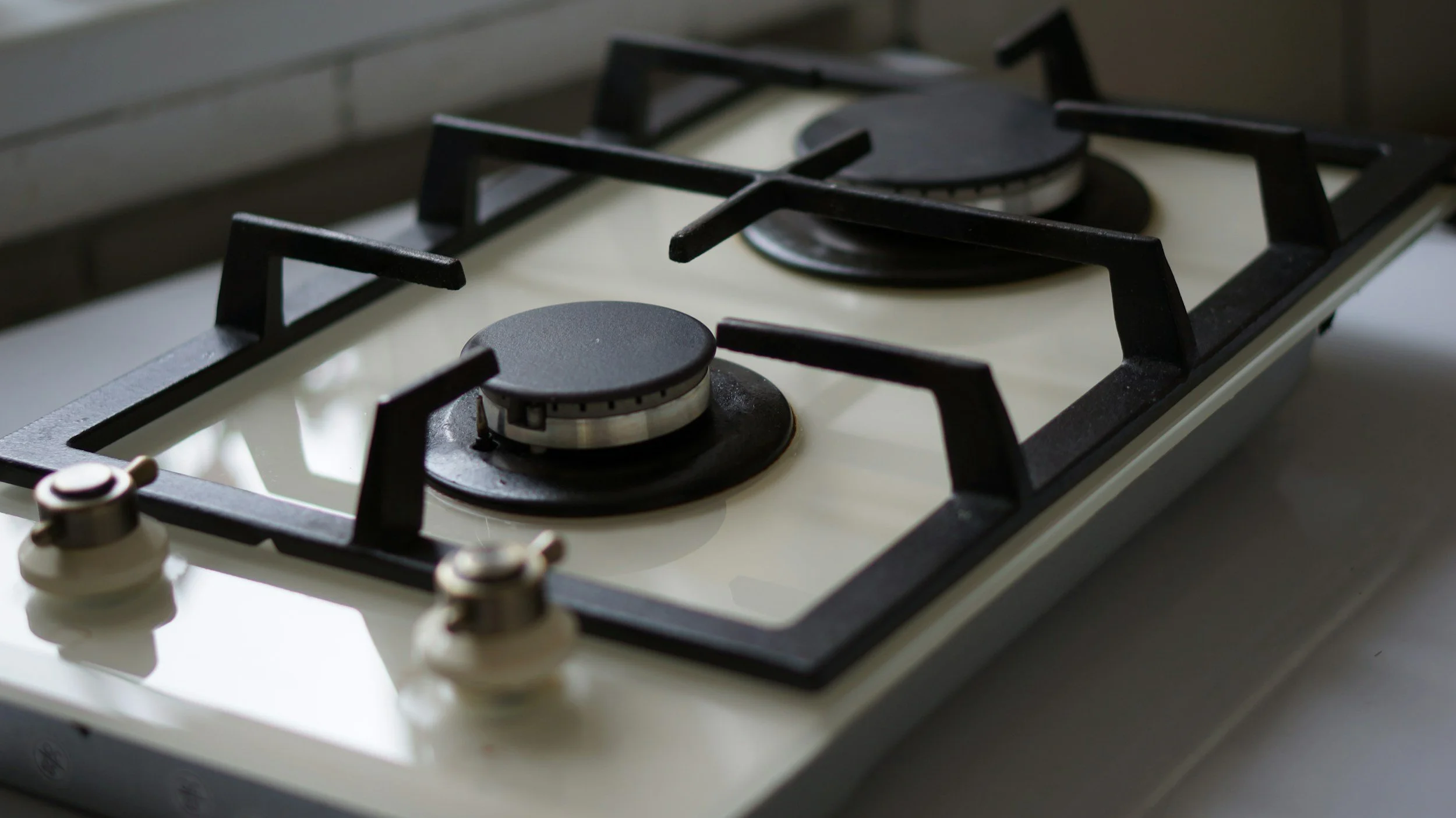 A gas stove with two burners, black grates, and white surface.