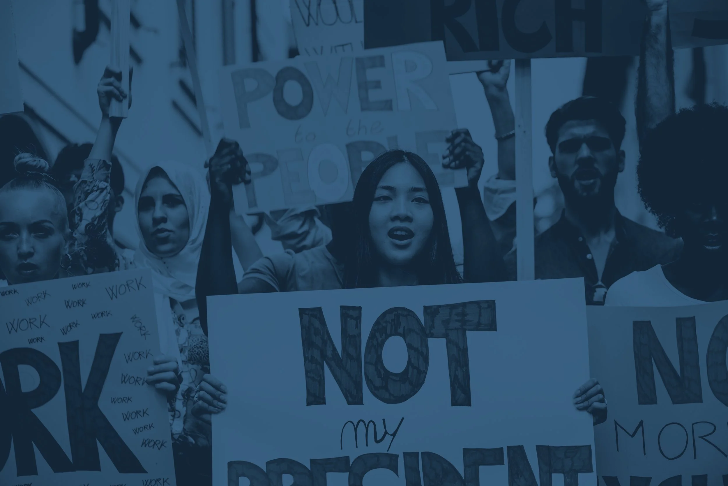 A diverse group of protesters holding up signs calling for justice and change, with messages like "NOT my president" and "Power to the people."