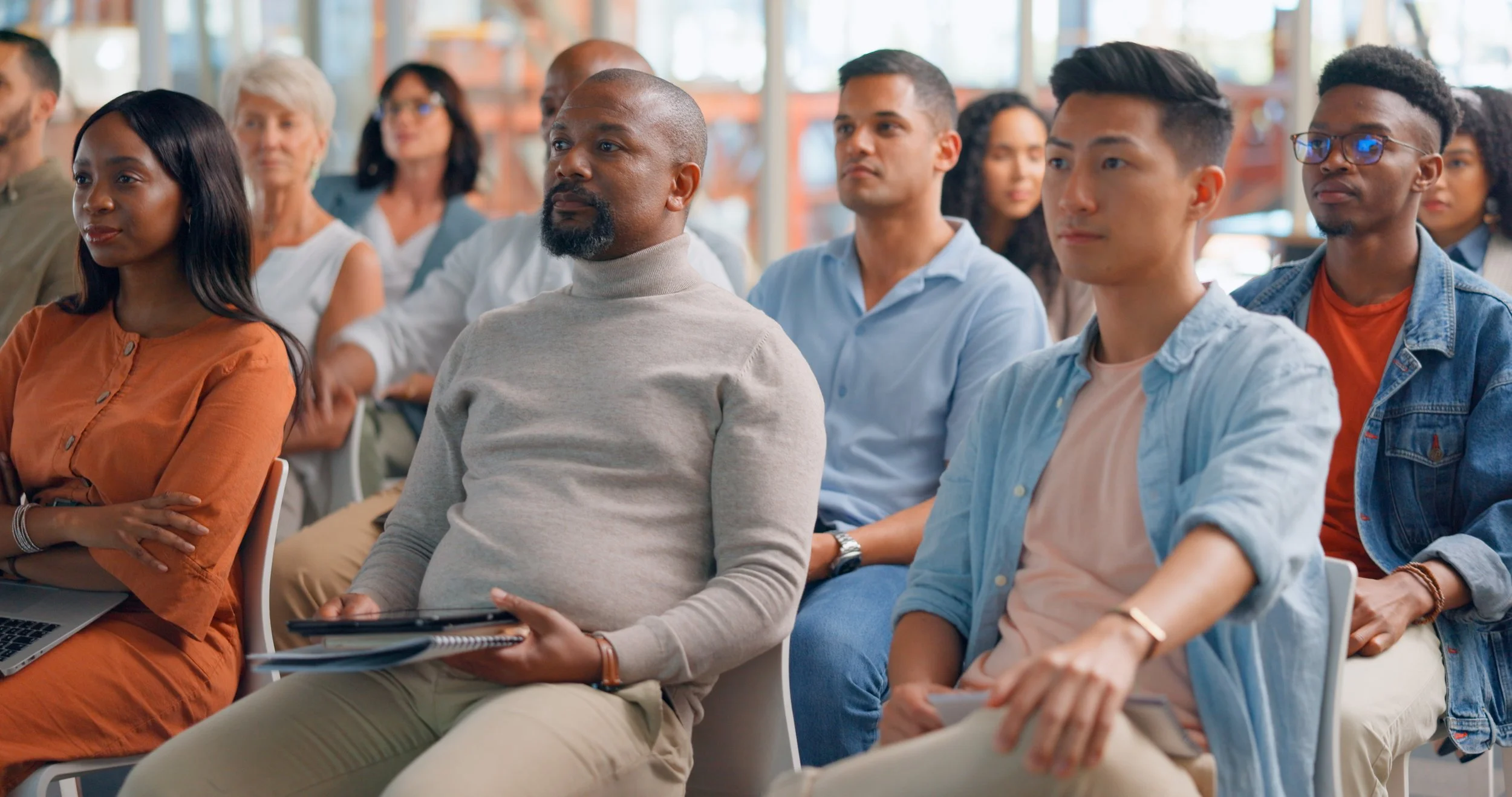 A diverse group of people attending a conference or seminar, sitting attentively in a meeting.