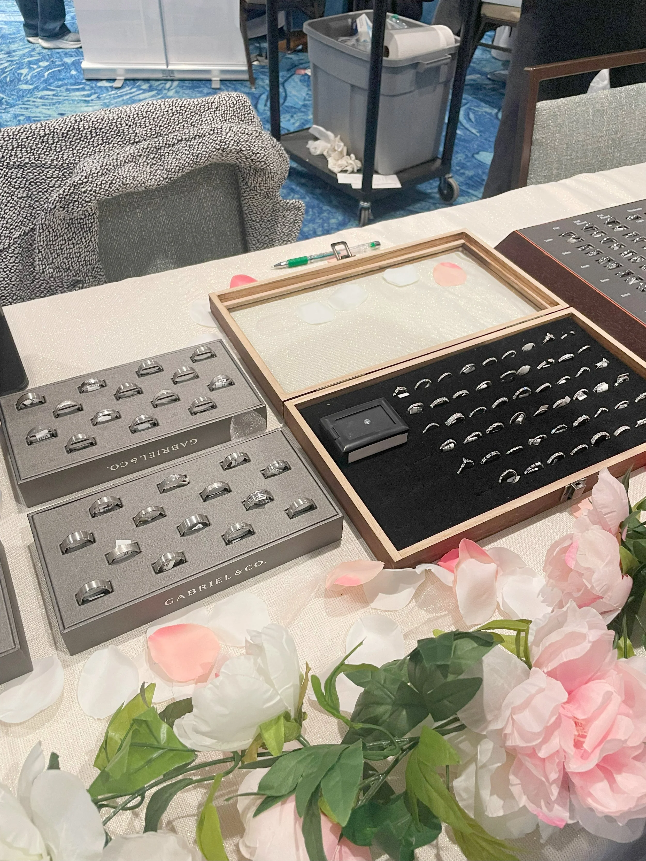 Display of wedding rings on a table, with pink and white flower petals.