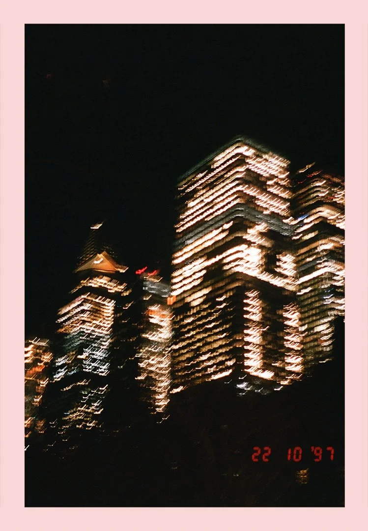 Blurry night photo of illuminated skyscrapers against dark sky, with a date stamp showing October 22, 1997.