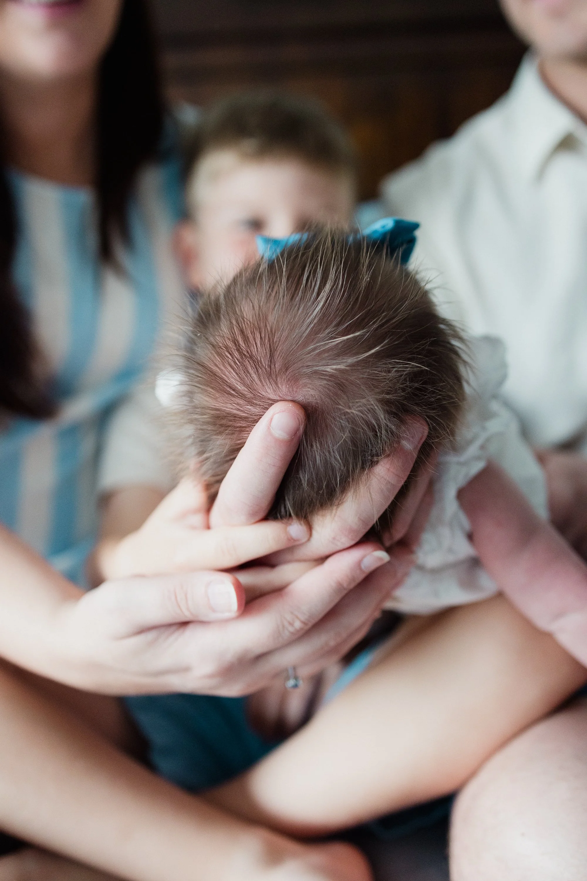 Child with hair being examined for lice by an adult woman, with other children in the background.