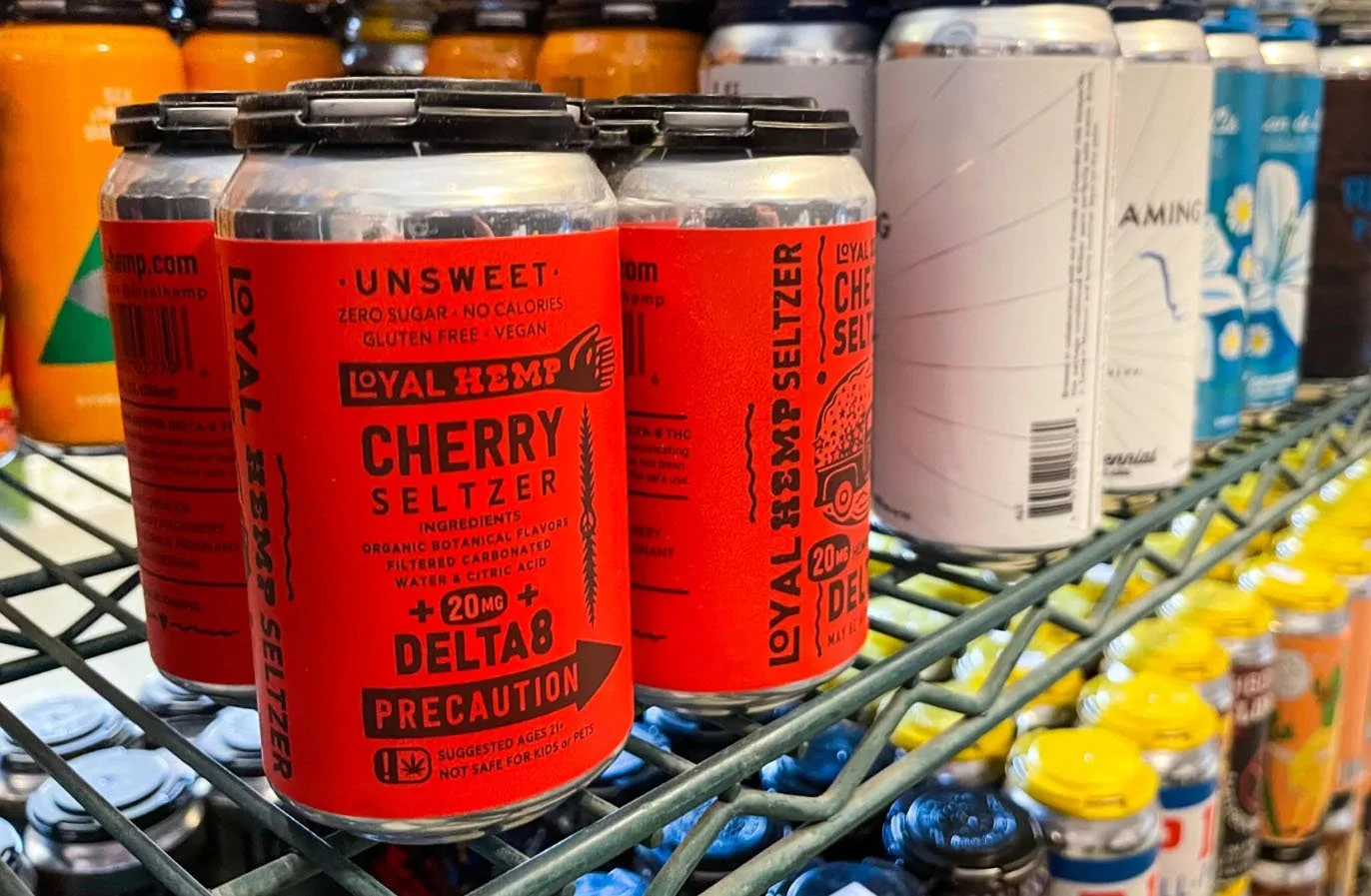 Cans of Loyal Hemp Cherry Seltzer with red labels on store shelf.
