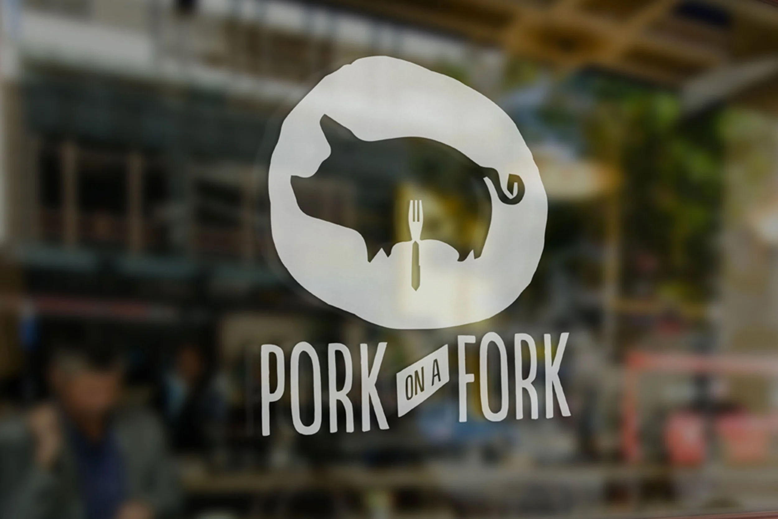 A window decal features a silhouette of a pig's head and the words "PORK ON A FORK". The background shows a blurry outdoor scene.