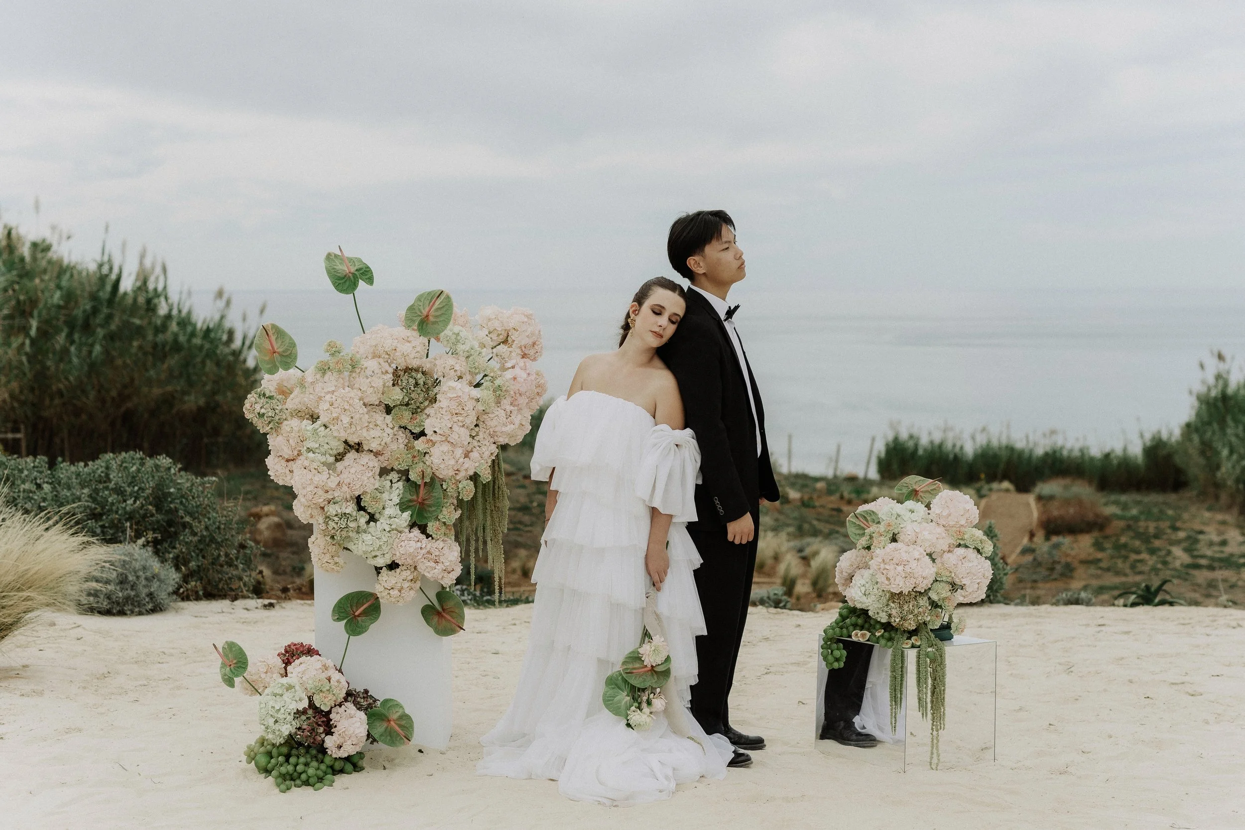 A romantic international couple celebrating their destination wedding on a stunning beachfront venue in Portugal. The ocean backdrop and golden light create perfect conditions for elegant wedding photography.
