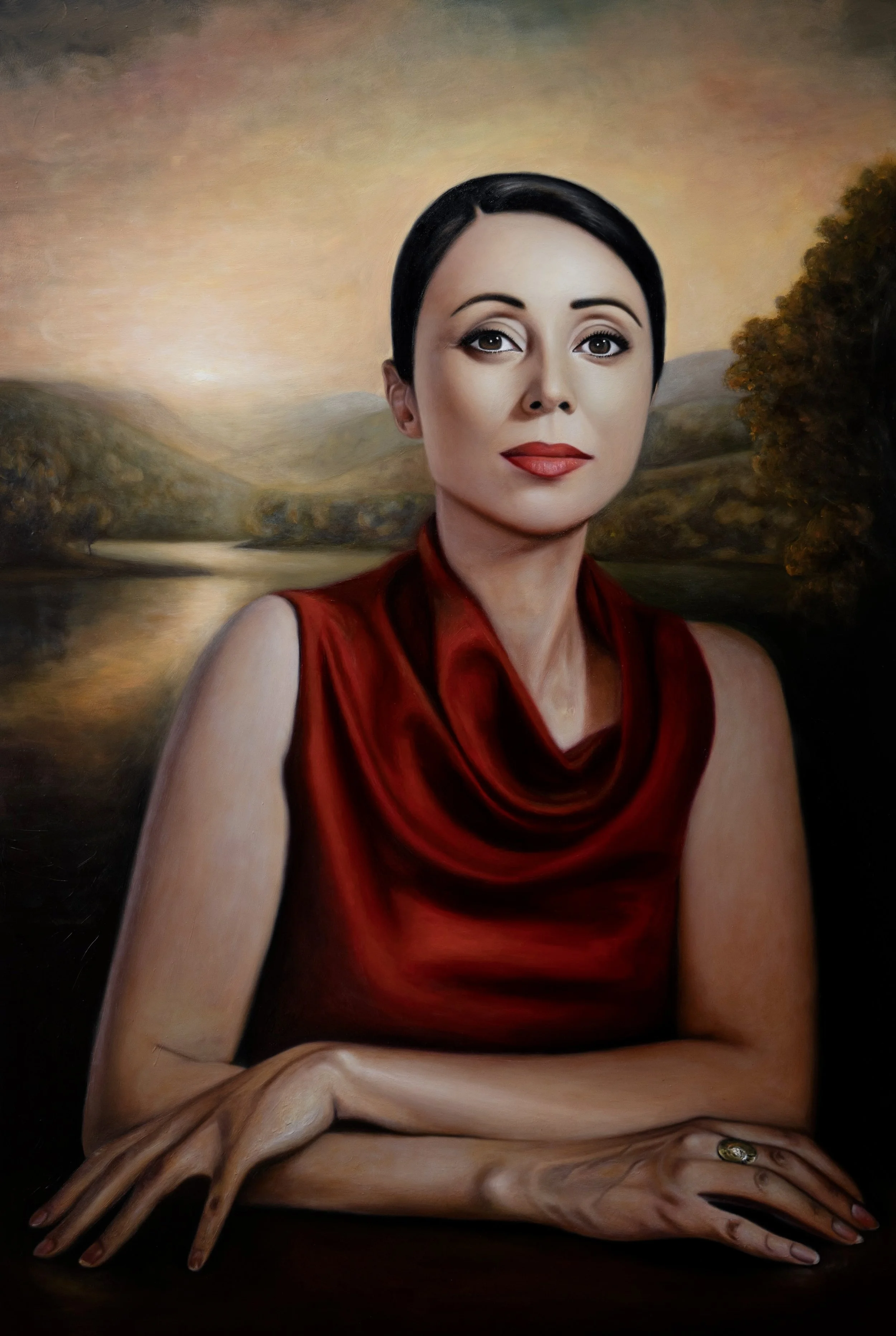 A portrait painting of a woman with short black hair, wearing a red dress, sitting with her arms crossed. The background features a landscape with hills, trees, and a body of water during sunset.