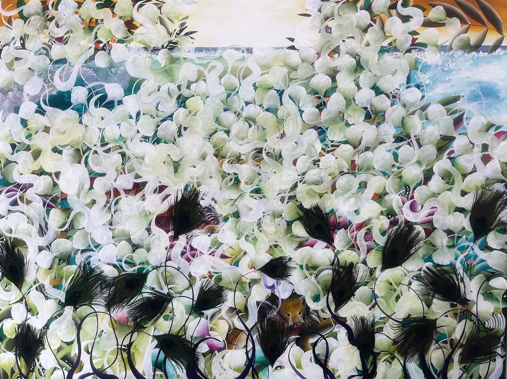 A decorative backdrop made of white flowers with dark centers and peacock feathers, arranged as a floral wall with an ocean view in the background.
