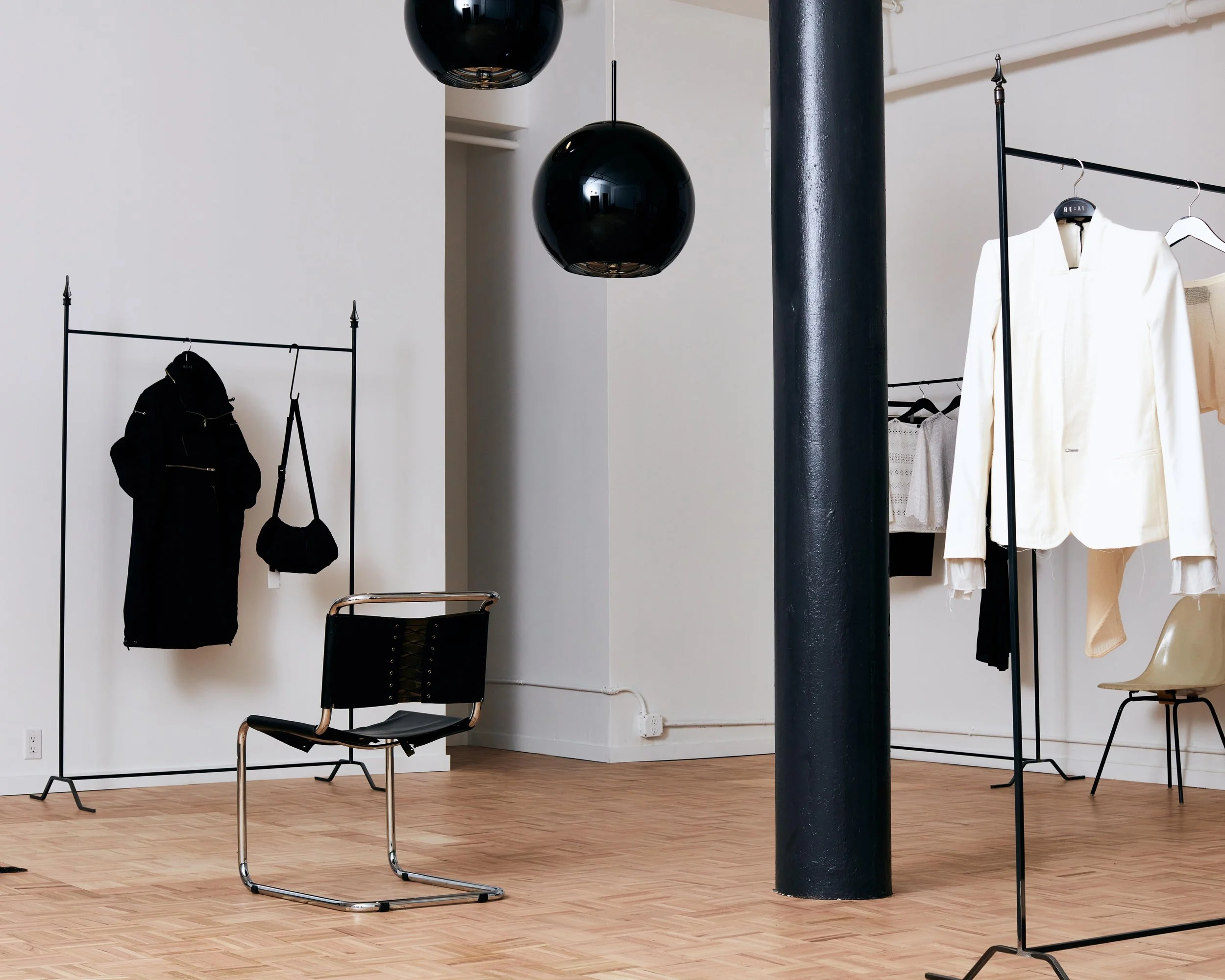 New York City Luxury Fashion store Re:al abayan. interior design photography for retail shop. set in a vast loft space big windows rod iron racks tom Dixon ball lights. moody lighting