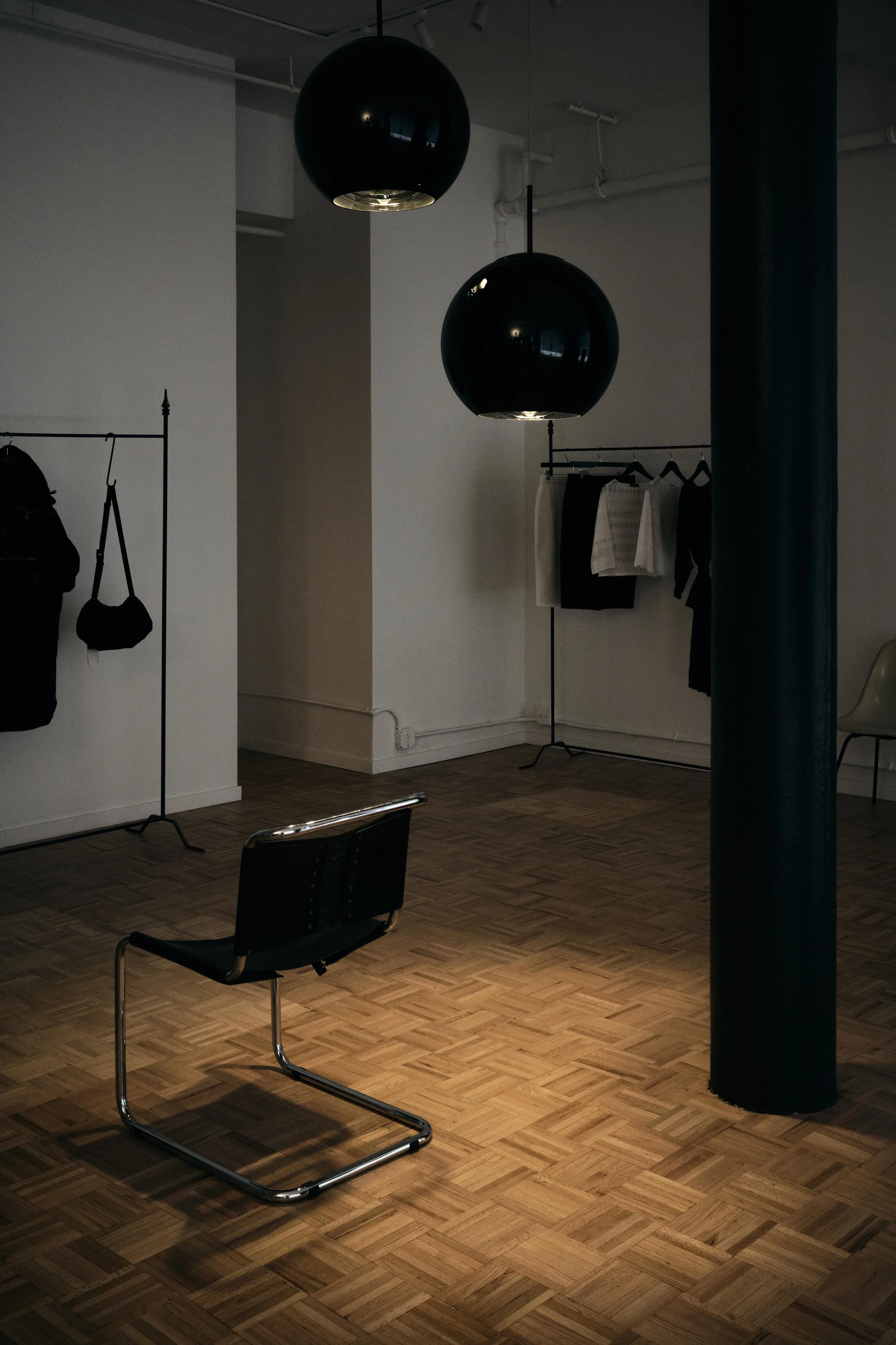 New York City Luxury Fashion store Re:al abayan. interior design photography for retail shop. set in a vast loft space big windows rod iron racks tom Dixon ball lights. cinematic moody lighting