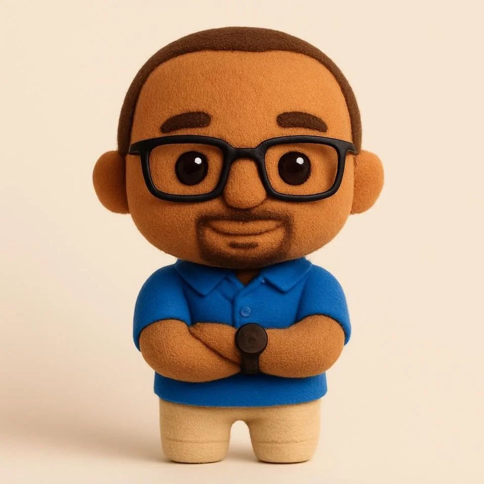 Knuffelpop van freelance verpleegkundige Haadi Mohammed Iddrisu met bril, blauwe polo, beige broek, korte haar, glimlach, armen over elkaar, op een lichte achtergrond.