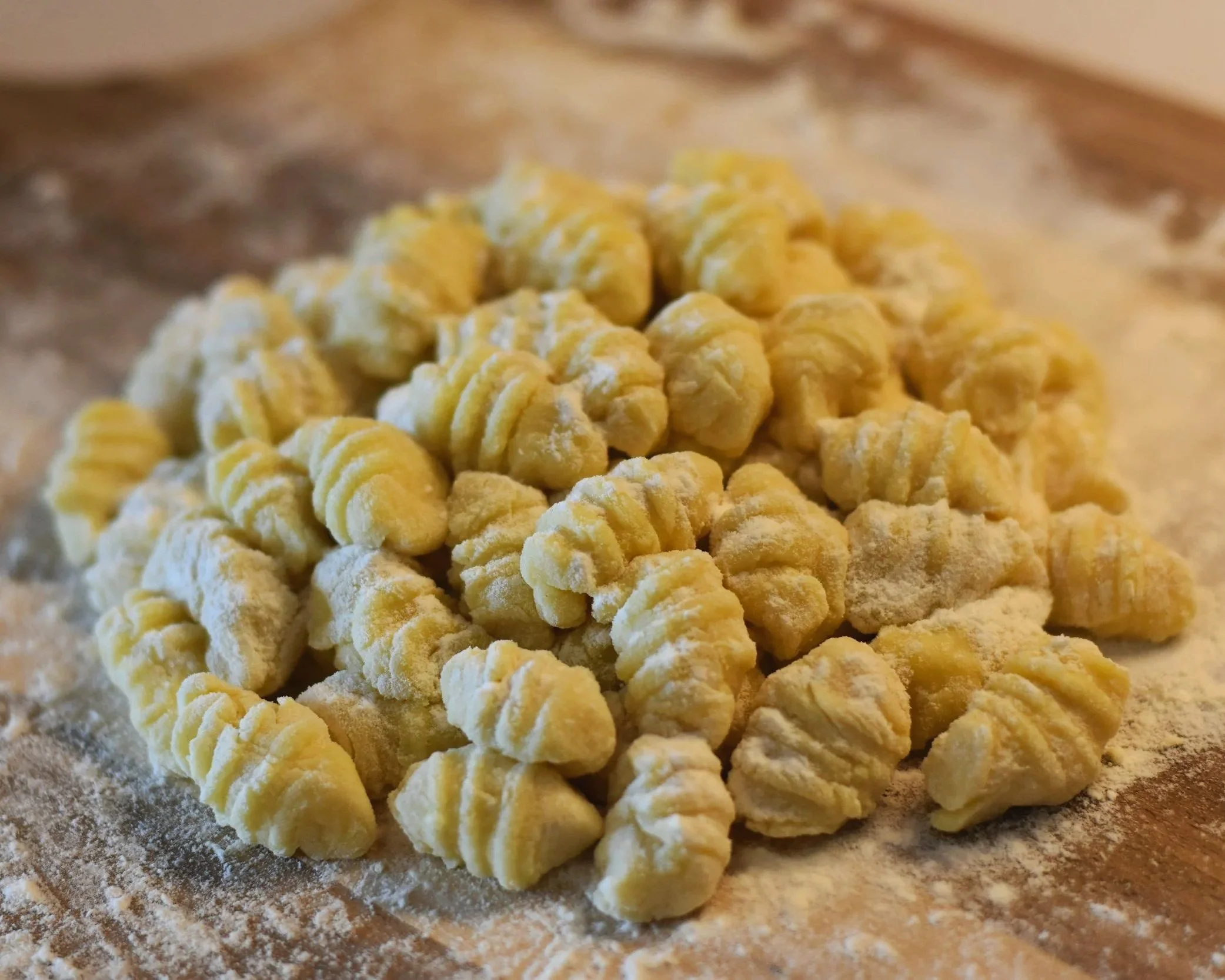 A pile of gnocchi on a cutting board covered in flour