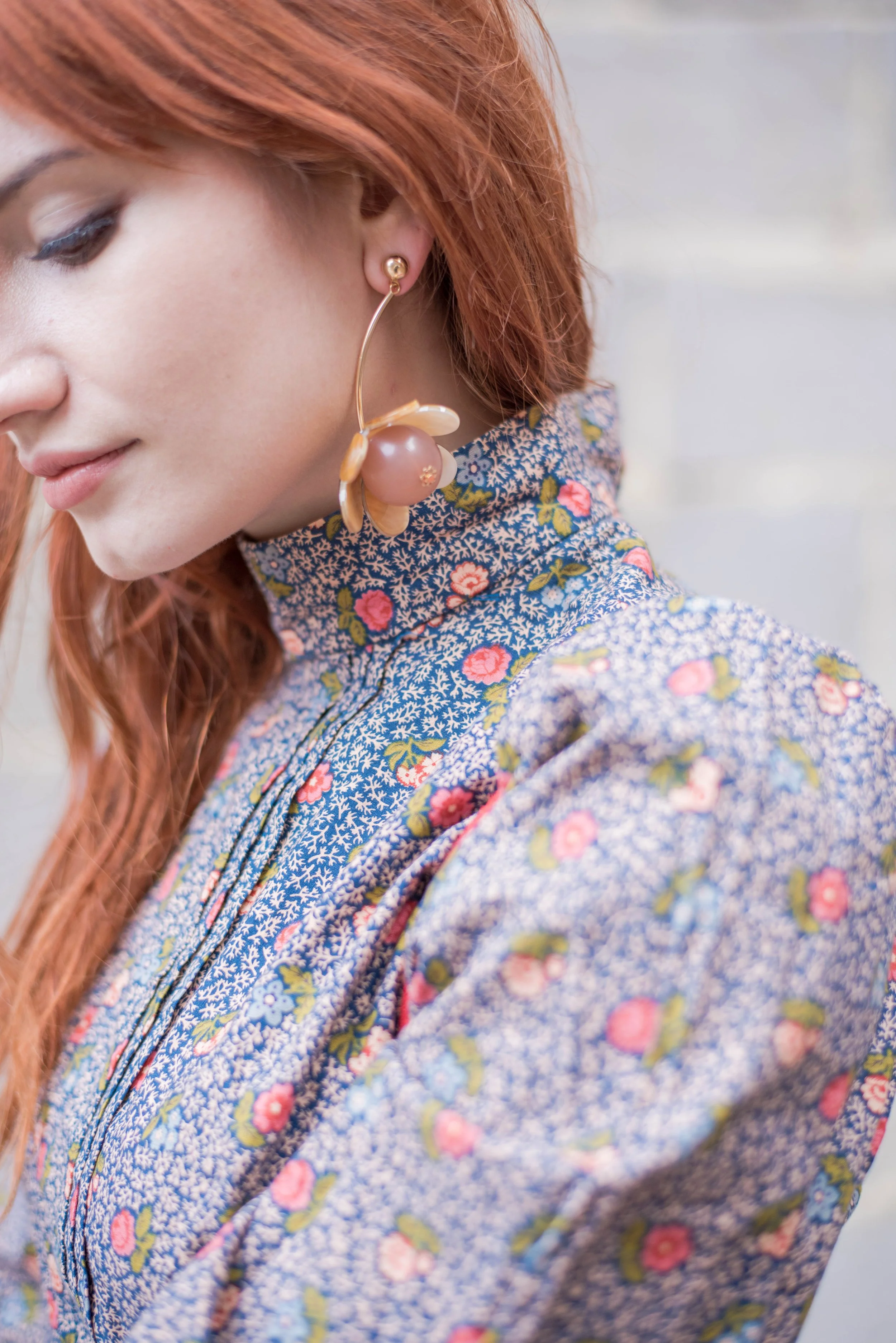 Close-up of floral statement earrings paired with a high-neck floral dress.