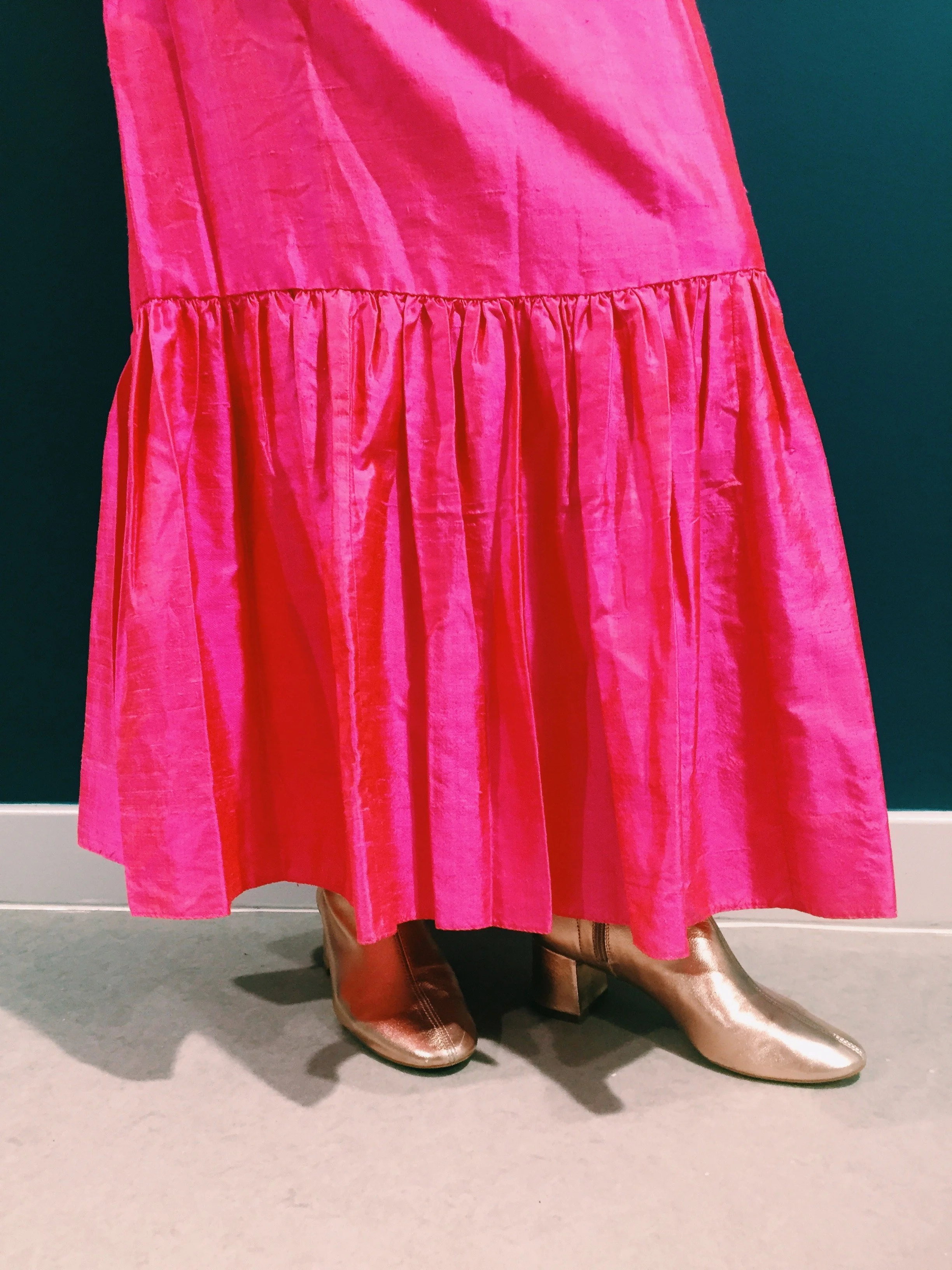 Close-up of metallic gold vintage ankle boots paired with a vibrant pink gathered silk dress, styled by Louisa Rogers for a bold retro-inspired fashion look.