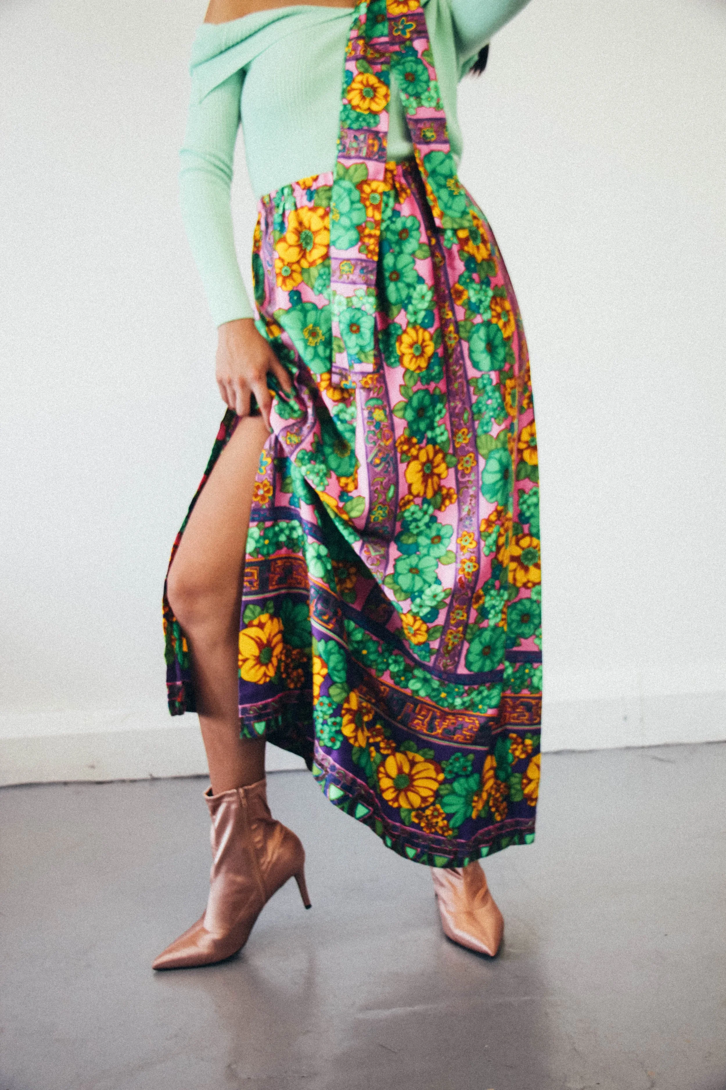Close-up of Annie wearing a vibrant vintage floral wrap skirt paired with rose gold satin ankle boots and a mint off-shoulder top, styled and photographed by Louisa Rogers.