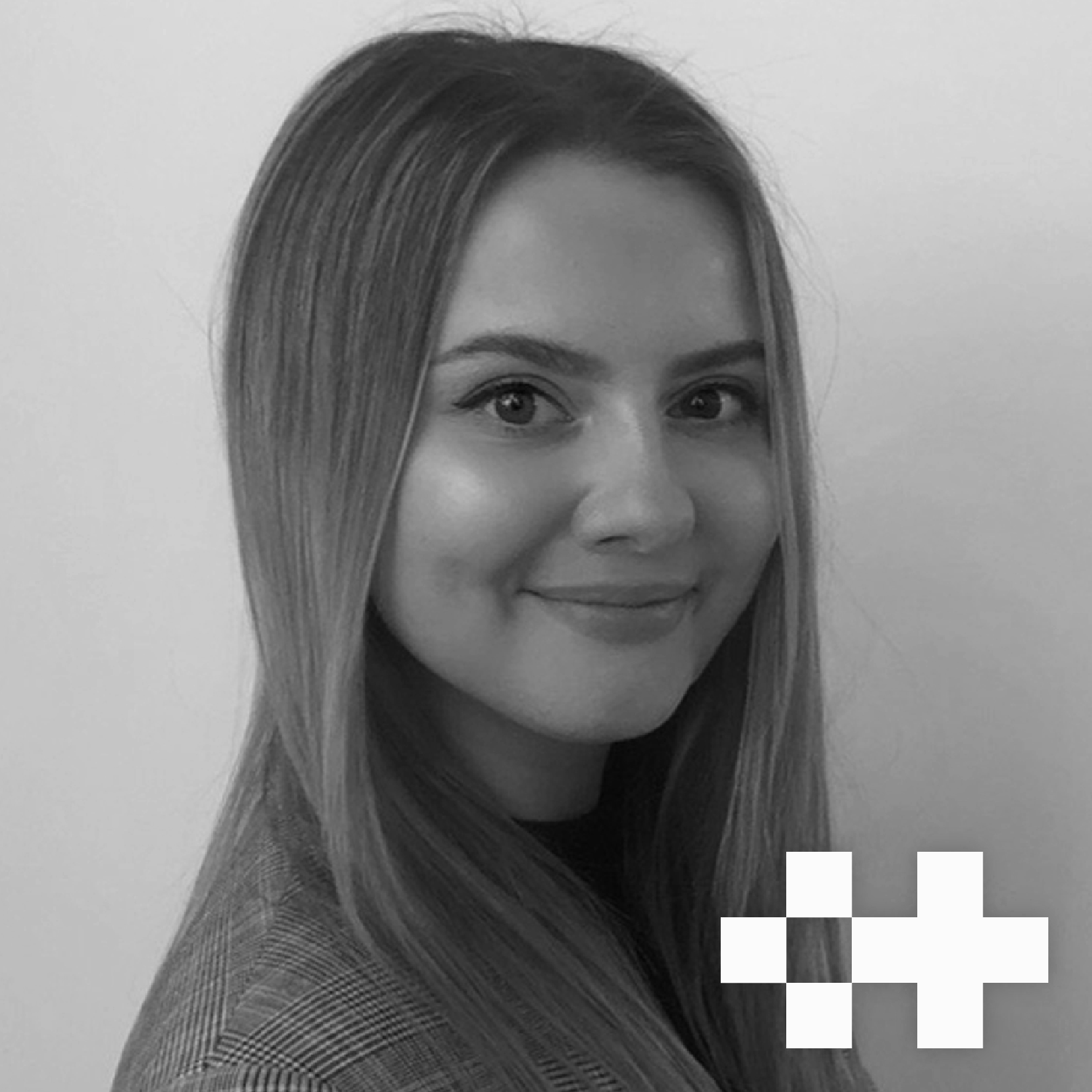 Black-and-white portrait of a smiling woman with long, straight hair, wearing a checkered blazer, against a plain background.
