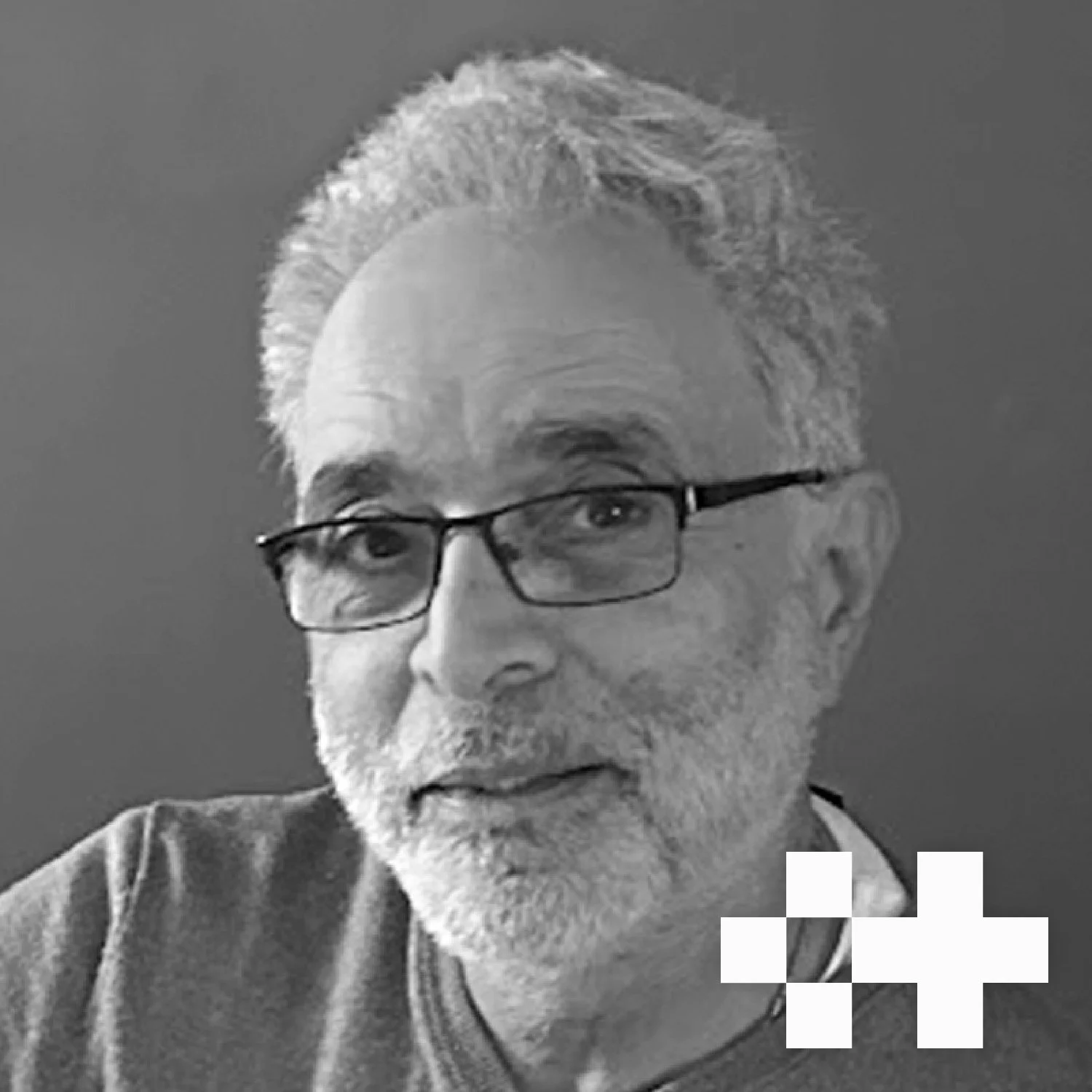 Black and white portrait of an older man with glasses, grey hair, and a beard, smiling slightly against a plain background.