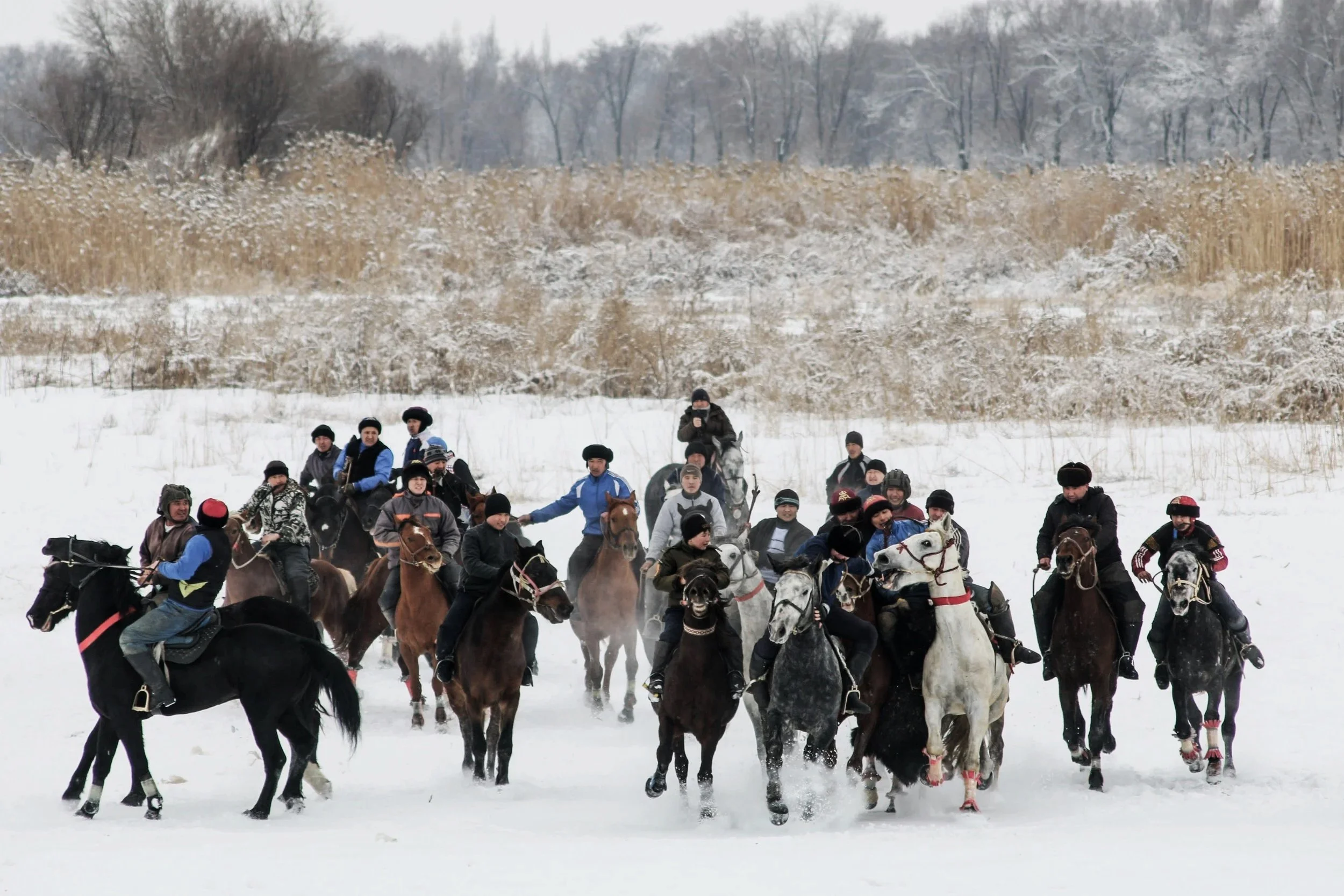 People riding horses across a snowy landscape during winter.