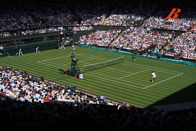 A tennis match in progress at a stadium filled with spectators, with players on the court and officials around.
