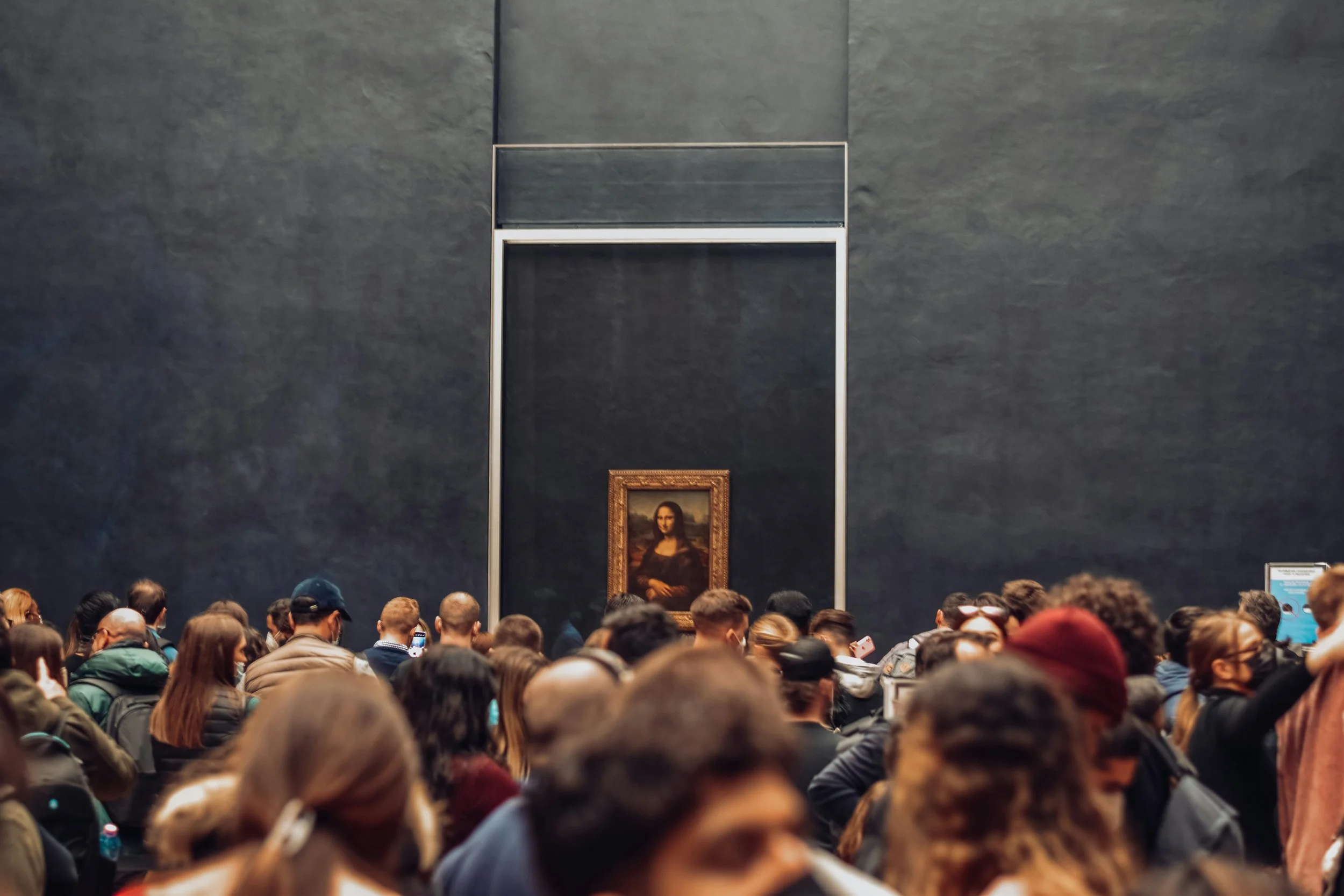 Large crowd of people viewing the Mona Lisa at the Louvre Museum in Paris, France.