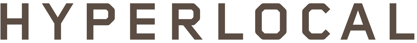 Close-up of a black sign with bold, uppercase, grayish-brown text that reads "HYPERLOCAL."