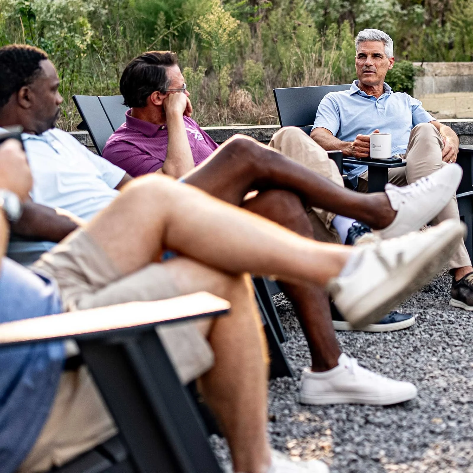 Group of men surrounding a fire pit with coffee