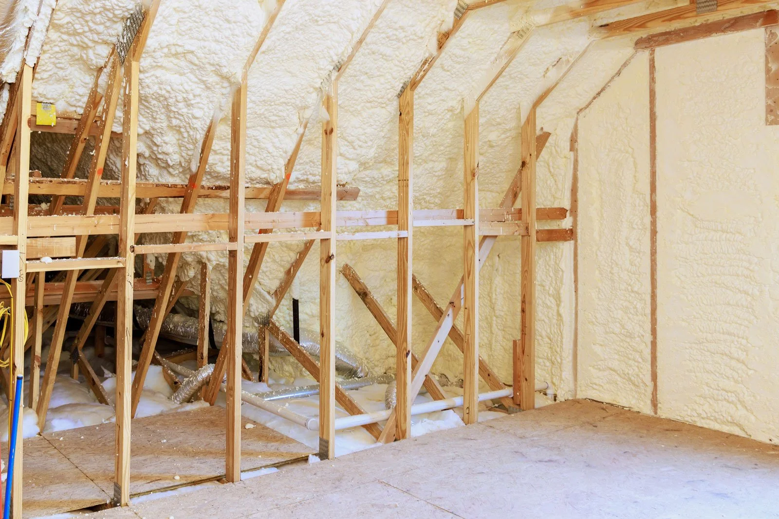 Interior view of a construction or renovation site showing wooden framing with insulation foam installed between the studs.