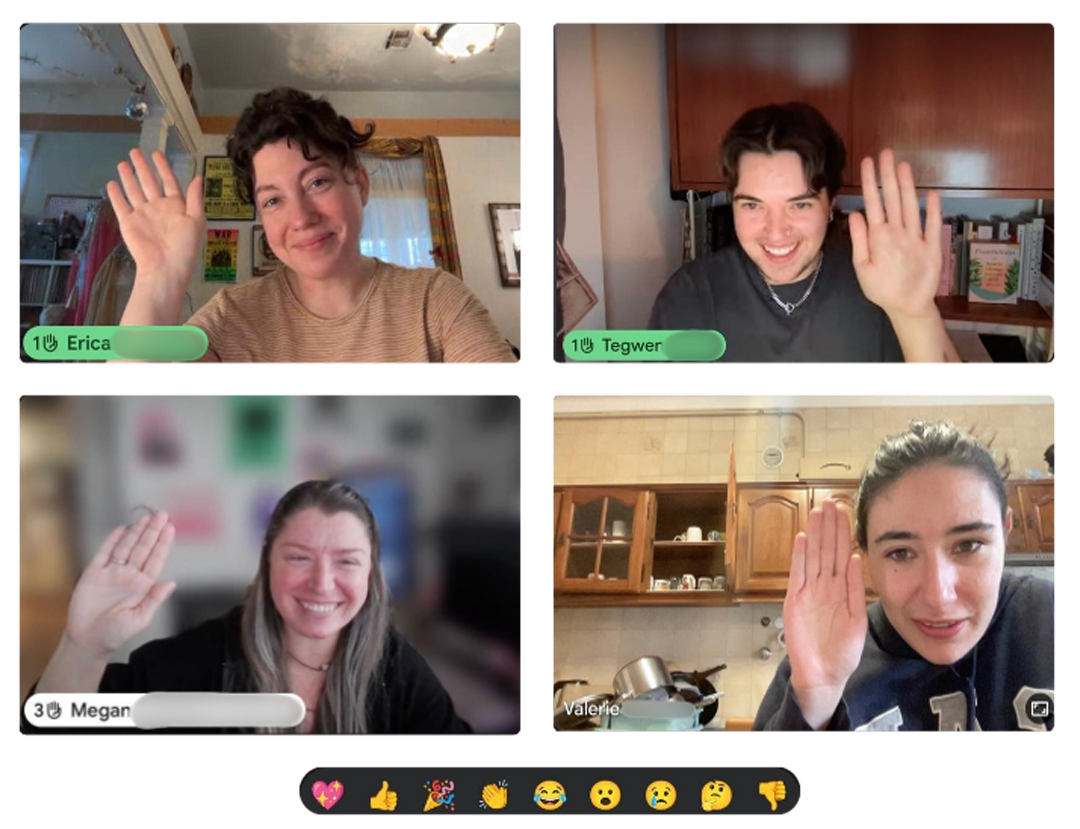 Four people on a video call, all raising their hands in a waving gesture, smiling at the camera.