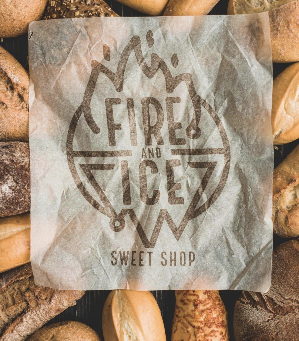 A piece of parchment paper with the words 'Fire and Ice' and 'Sweet Shop' written on it, placed over assorted baked goods such as cookies and bread.