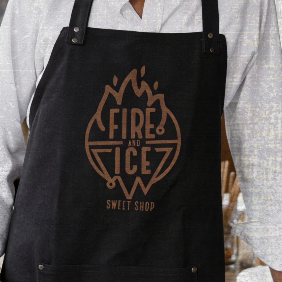 Person wearing a white shirt with a black apron that has a logo reading 'Fire and Ice Sweet Shop' and a flame and ice graphic.