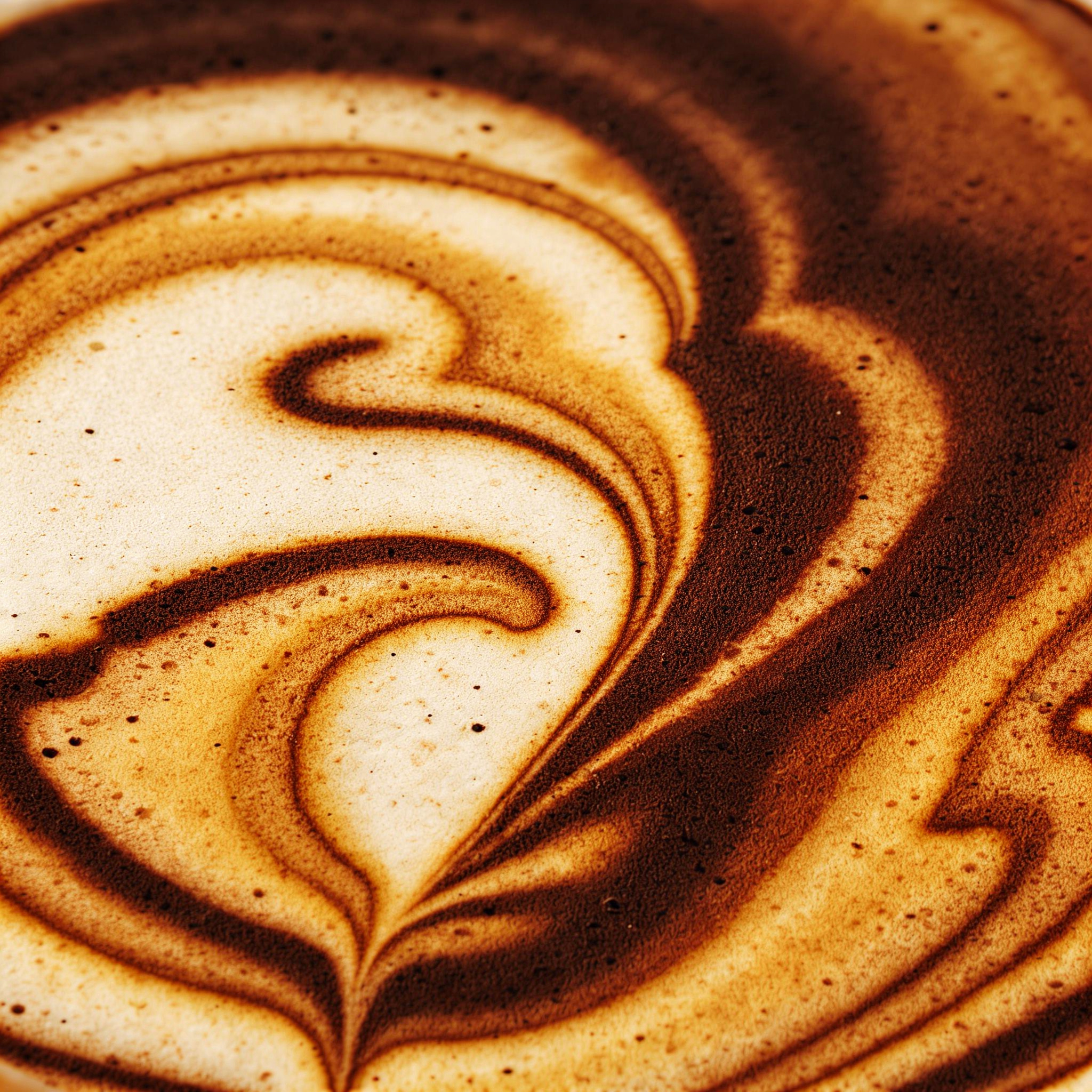 Close-up of a coffee foam with a cinnamon powder pattern resembling a heart.