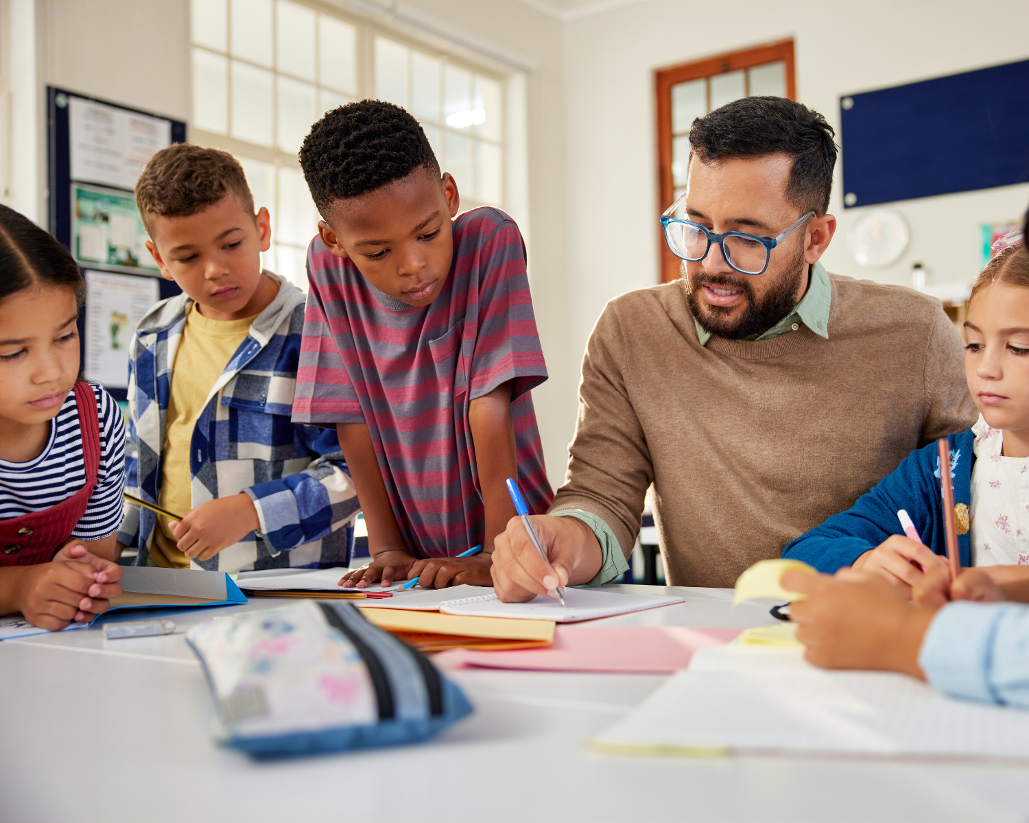 A teacher helping students with schoolwork in a classroom.