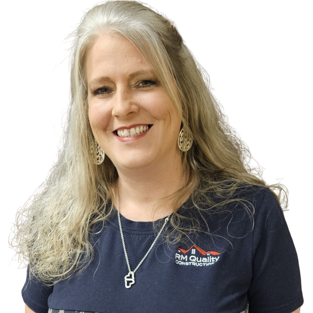 A smiling woman with long blonde hair wearing a dark t-shirt with a construction company logo, large earrings, and a necklace.