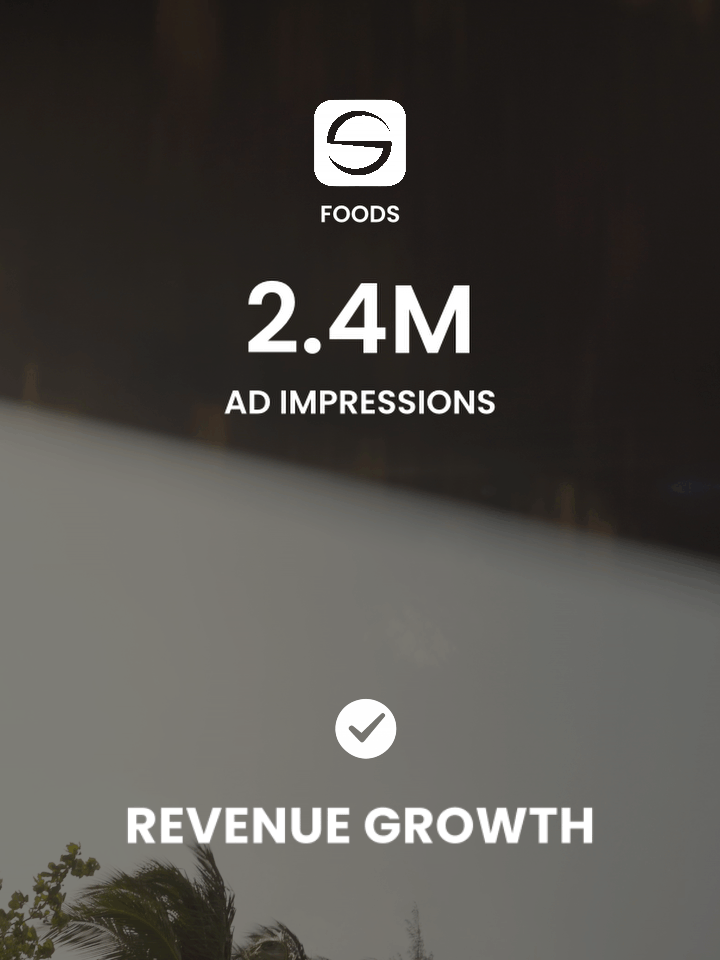 Aerial view of a coastline with clear blue water and a residential area with houses and greenery along the shore.