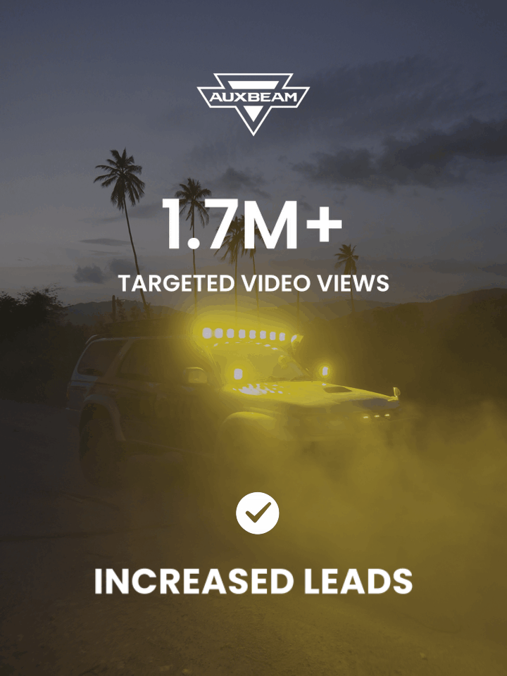 A woman is sitting on a kitchen counter while being filmed by a person operating a camera. Two men are preparing coffee, one pouring water from a kettle, and the other holding a camera on a stabilizer.